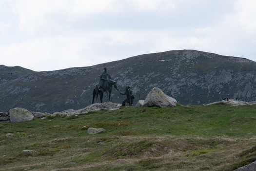 View of the equestrian statue at Sankt Gotthard Pass surrounded by rocky mountain peaks and alpine meadows under a cloudy sky in Airolo Ticino Switzerland.