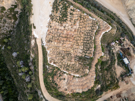 Aerial view of a quarry site with terraced excavation dirt roads and surrounding vegetation in Teulada Valencian Community Spain.