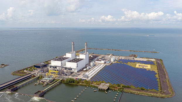 Aerial view of the Maxima Power Plant with its industrial buildings chimneys and adjacent solar panel field situated on the coast in Lelystad Flevoland Netherlands. Aerial view of the Maxima Power Plant with its industrial buildings chimneys and adjacent solar panel field situated on the coast in Lelystad Flevoland Netherlands.
