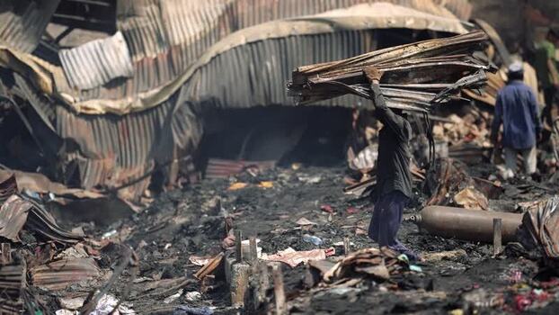 View of a man carrying debris through a fire damaged area Bangladesh. View of a man carrying debris through a fire damaged area Bangladesh.