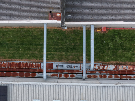 Aerial view of industrial site featuring corrugated metal roofs weathered rusty pipes and a strip of green grass in Melbourne VIC Australia.