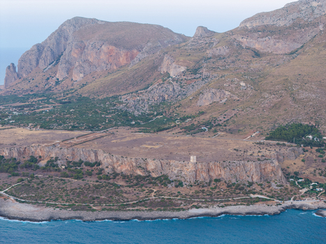 Aerial view of Riserva Naturale Orientata dello Zingaro featuring rugged coastal cliffs a historic watchtower and the Mediterranean sea in San Vito Lo Capo Sicilia Italy. Aerial view of Riserva Naturale Orientata dello Zingaro featuring rugged coastal cliffs a historic watchtower and the Mediterranean sea in San Vito Lo Capo Sicilia Italy.