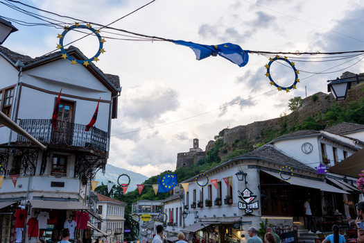 Gjirokaster Albania 09 June 2026 View of traditional Ottoman houses and the historic fortress on the hill with European Union flags and decorations hanging over the old town street.