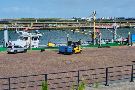 Den Oever Netherlands 20 May 2026 View of Vissershaven with a fishing boat docked at the quay next to a yellow forklift and a parked car under a blue sky. Den Oever Netherlands 20 May 2026 View of Vissershaven with a fishing boat docked at the quay next to a yellow forklift and a parked car under a blue sky.