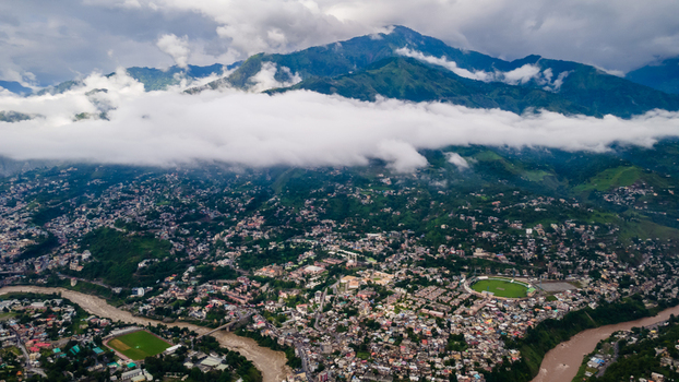 Aerial view of the urban landscape of Muzaffarabad city nestled in a valley with a winding river and surrounded by green mountains under low clouds Muzaffarabad Azad Kashmir Pakistan. Aerial view of the urban landscape of Muzaffarabad city nestled in a valley with a winding river and surrounded by green mountains under low clouds Muzaffarabad Azad Kashmir Pakistan.