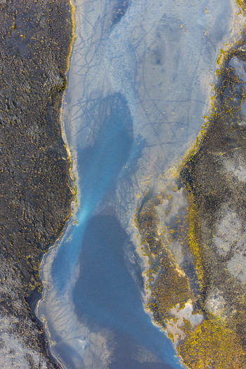 Aerial view of a winding river flowing through dark volcanic terrain with vibrant mossy patches in Selfoss Sveitarfelagid Arborg Iceland. Aerial view of a winding river flowing through dark volcanic terrain with vibrant mossy patches in Selfoss Sveitarfelagid Arborg Iceland.