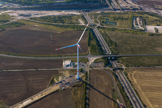 Aerial view of a wind turbine standing in the industrial landscape of the Schleenhain lignite open cast mine with surrounding fields and infrastructure in Zwenkau Saxony Germany.