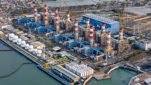 Aerial view of a large industrial power plant with tall smokestacks numerous storage tanks and complex infrastructure situated along the coast in Semarang Central Java Indonesia. Aerial view of a large industrial power plant with tall smokestacks numerous storage tanks and complex infrastructure situated along the coast in Semarang Central Java Indonesia.