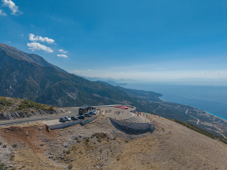 Aerial view of the Llogara Pass viewing platform with visitors parked cars and a panoramic mountain landscape overlooking the Ionian Sea coastline in Llogara Vlore County Albania. Aerial view of the Llogara Pass viewing platform with visitors parked cars and a panoramic mountain landscape overlooking the Ionian Sea coastline in Llogara Vlore County Albania.