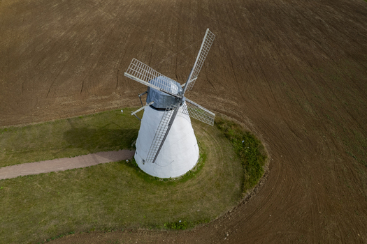 Aerial view of the historic white windmill at Vihula Manor surrounded by cultivated brown fields and green grass in Vihula Laane Viru County Estonia.