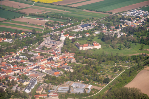 Aerial view of the historic village center featuring the parish church and castle surrounded by green fields and residential houses in Trautmannsdorf an der Leitha Niederosterreich Austria. Aerial view of the historic village center featuring the parish church and castle surrounded by green fields and residential houses in Trautmannsdorf an der Leitha Niederosterreich Austria.