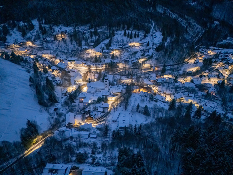 Aerial view of the historic village of Spania Dolina with snow covered rooftops and glowing lights nestled in a dark winter valley Spania Dolina Banska Bystrica Region Slovakia. Aerial view of the historic village of Spania Dolina with snow covered rooftops and glowing lights nestled in a dark winter valley Spania Dolina Banska Bystrica Region Slovakia.