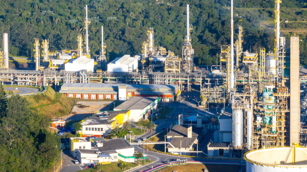 Aerial view of the petrochemical complex featuring industrial towers pipelines and storage tanks surrounded by lush forest in Santo Andre State of Sao Paulo Brazil.