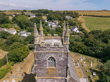 Aerial view of St Ildierna s Church with its historic stone tower and surrounding graveyard nestled among lush green trees and rural fields in Lansallos England United Kingdom. Aerial view of St Ildierna s Church with its historic stone tower and surrounding graveyard nestled among lush green trees and rural fields in Lansallos England United Kingdom.
