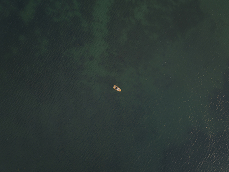 Aerial view of a small boat floating on the calm dark green waters of the Black Sea near the historic town of Nessebar Burgas Bulgaria. Aerial view of a small boat floating on the calm dark green waters of the Black Sea near the historic town of Nessebar Burgas Bulgaria.