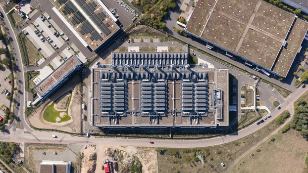 Aerial view of a large industrial facility with extensive rooftop HVAC units surrounded by parking lots and green spaces in Dietzenbach Hessen Germany. Aerial view of a large industrial facility with extensive rooftop HVAC units surrounded by parking lots and green spaces in Dietzenbach Hessen Germany.