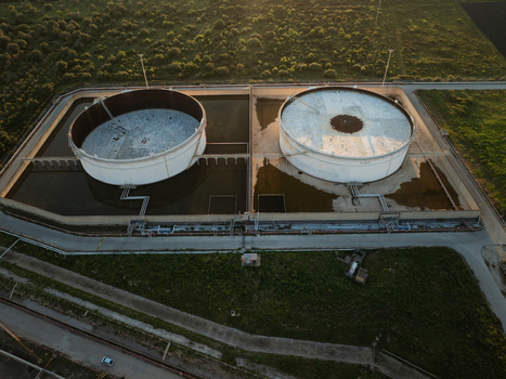 Aerial view of two large industrial storage tanks within a containment area surrounded by green fields in Augusta Sicily Italy. Aerial view of two large industrial storage tanks within a containment area surrounded by green fields in Augusta Sicily Italy.