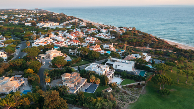 Aerial view of luxury villas with swimming pools nestled among pine trees along the coastline of Lagos Faro District Portugal.