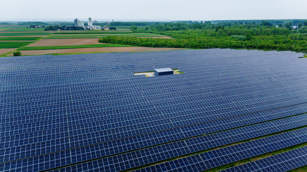 Aerial view of a large solar panel array in a rural landscape with green fields and distant industrial buildings Sabac Vojvodina Serbia.