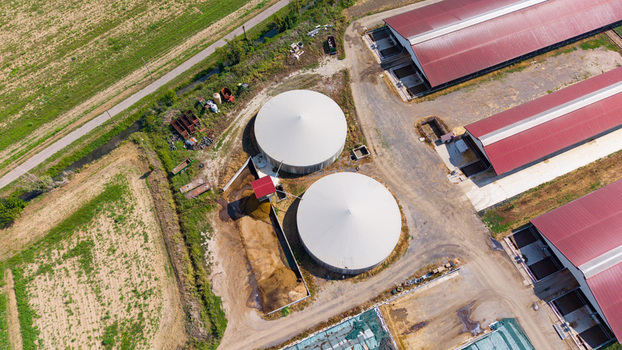 Aerial view of a cattle farm featuring two large white circular silos and red roofed agricultural buildings surrounded by fields in San Giuliano Milanese Lombardy Italy. Aerial view of a cattle farm featuring two large white circular silos and red roofed agricultural buildings surrounded by fields in San Giuliano Milanese Lombardy Italy.