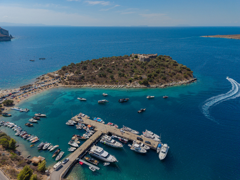 Aerial view of the Castle of Porto Palermo situated on a peninsula with a bustling marina filled with yachts and boats surrounded by turquoise waters in Porto Palermo Qarku i Vlores Albania.