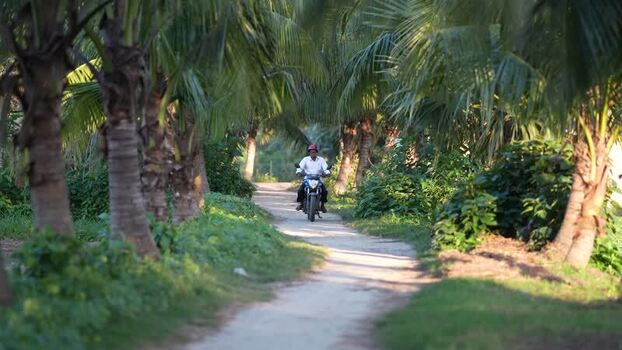 View of a man riding a motorcycle on a rural path Bangladesh.