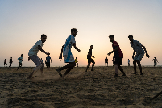 Sri Lanka 23 January 2026 View of a group of young men playing football on a sandy beach during a golden sunset.