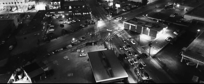 Aerial view of a busy street intersection at night with illuminated roads moving vehicles and surrounding urban buildings in Los Angeles California United States.