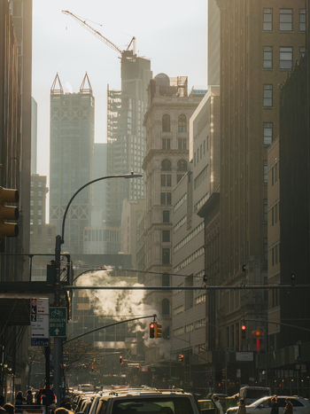 View of a busy street in New York City with skyscrapers a construction crane and steam rising from the ground in New York New York United States.
