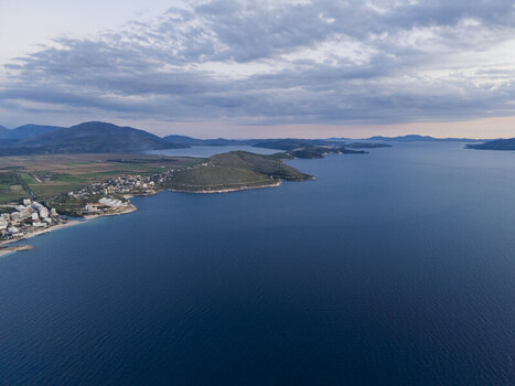 Aerial view of the coastline of Saranda featuring the blue Ionian Sea coastal hills and urban development in Saranda Vlore County Albania. Aerial view of the coastline of Saranda featuring the blue Ionian Sea coastal hills and urban development in Saranda Vlore County Albania.