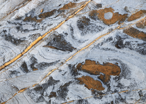 View of the unique geological sandstone patterns and veins on the rocky coast of Calafuria Toscana Italy.