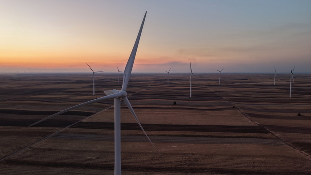 Aerial view of wind turbines standing in vast agricultural fields during a serene sunset in Vladimirovac Vojvodina Serbia.