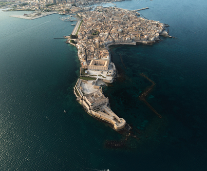 Aerial view of the Island of Ortigia and Castello Maniace surrounded by the deep blue Mediterranean Sea in Syracuse Sicily Italy. Aerial view of the Island of Ortigia and Castello Maniace surrounded by the deep blue Mediterranean Sea in Syracuse Sicily Italy.