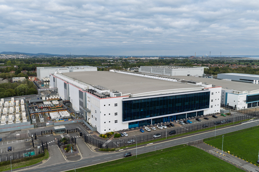 Aerial view of a large modern data center facility with cooling infrastructure and parking area United Kingdom.