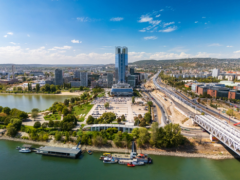 Aerial view of Mol Tower and Budapest skyline along the Danube riverbank with modern office buildings bridges roads and urban parks in the Hungarian capital. Aerial view of Mol Tower and Budapest skyline along the Danube riverbank with modern office buildings bridges roads and urban parks in the Hungarian capital.