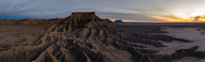 Aerial view of the dramatic eroded desert landscape and rugged rock formations of the Caineville Badlands during golden hour in Caineville Utah United States.