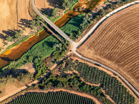 Aerial view of a river flowing under a bridge through agricultural fields and vineyards in Andalusia Spain. Aerial view of a river flowing under a bridge through agricultural fields and vineyards in Andalusia Spain.