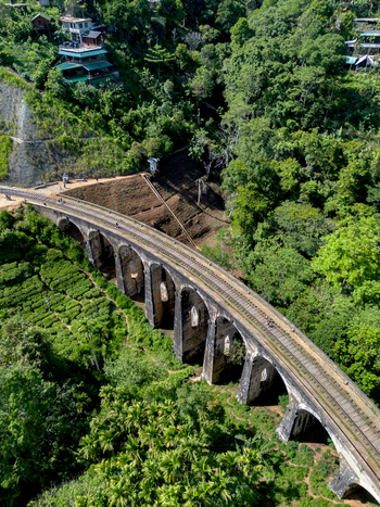 Aerial view of the historic Nine Arch Bridge surrounded by lush green tea plantations and dense forest in Demodara Uva Province Sri Lanka. Aerial view of the historic Nine Arch Bridge surrounded by lush green tea plantations and dense forest in Demodara Uva Province Sri Lanka.