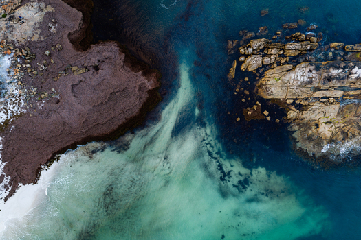 Aerial view of the rugged coastline of Torndirrup National Park with dark rock formations contrasting against turquoise and deep blue ocean waters in Albany Western Australia Australia. Aerial view of the rugged coastline of Torndirrup National Park with dark rock formations contrasting against turquoise and deep blue ocean waters in Albany Western Australia Australia.