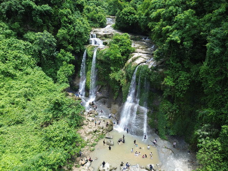 Aerial view of the lush Sahasradhara waterfall in Sitakund where people swim in the natural pool surrounded by dense forest and rocky terrain Sitakund Chittagong Division Bangladesh. Aerial view of the lush Sahasradhara waterfall in Sitakund where people swim in the natural pool surrounded by dense forest and rocky terrain Sitakund Chittagong Division Bangladesh.
