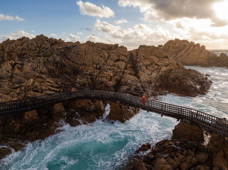 Aerial view of Canal Rocks Bridge with a person on the wooden footbridge over crashing turquoise waves and rugged granite rock formations in Yallingup Western Australia Australia. Aerial view of Canal Rocks Bridge with a person on the wooden footbridge over crashing turquoise waves and rugged granite rock formations in Yallingup Western Australia Australia.