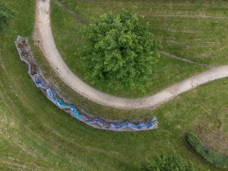 Aerial view of a meandering pathway winding around a vibrant green tree and colorful graffiti art C&eacute;zannestraat Almere Flevoland Netherlands.