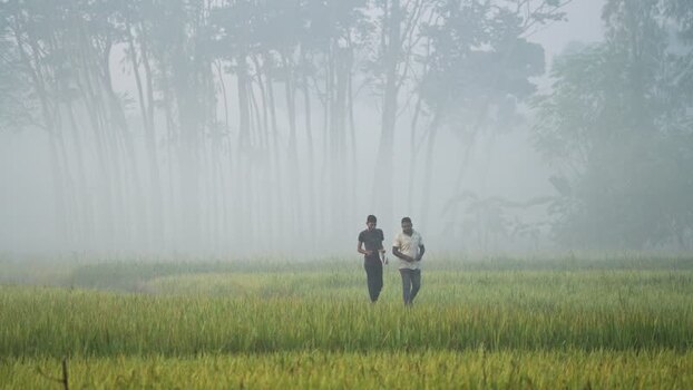 View of two men walking in a foggy field Bangladesh.