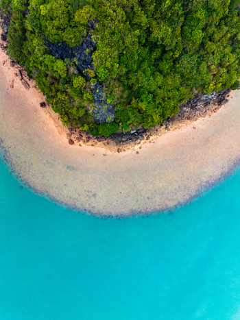 Aerial view of a lush green tropical island coastline with rocky cliffs and sandy beach meeting the clear turquoise water in Vietnam. Aerial view of a lush green tropical island coastline with rocky cliffs and sandy beach meeting the clear turquoise water in Vietnam.