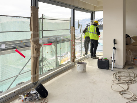 View of construction workers in yellow vests and hard hats working inside a building under renovation with scaffolding visible through large windows Avcilar Istanbul Turkiye. View of construction workers in yellow vests and hard hats working inside a building under renovation with scaffolding visible through large windows Avcilar Istanbul Turkiye.