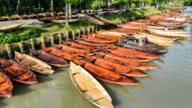 Aerial view of wooden boats resting on the shimmering riverbanks a symphony of warm browns against the vibrant green foliage Pirojpur Pourashava Barisal Division Bangladesh. Aerial view of wooden boats resting on the shimmering riverbanks a symphony of warm browns against the vibrant green foliage Pirojpur Pourashava Barisal Division Bangladesh.