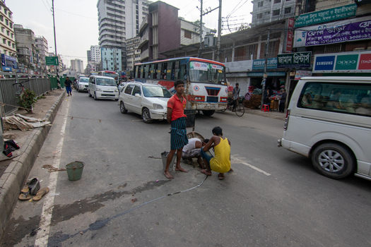 Dhaka Bangladesh 18 April 2018 View of workers performing maintenance on a utility line in the middle of a busy city street with traffic and urban buildings. Dhaka Bangladesh 18 April 2018 View of workers performing maintenance on a utility line in the middle of a busy city street with traffic and urban buildings.