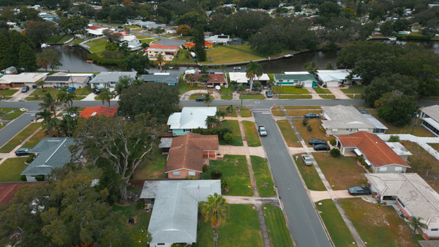Aerial view of a residential neighborhood featuring single family homes lush green lawns palm trees and a canal running through the area in Clearwater Florida United States.