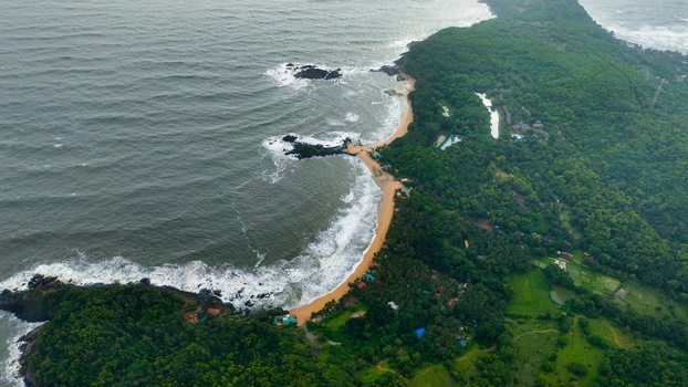 Aerial view of Om Beach Birdview Point showcasing the crescent shaped coastline lush green forests rocky outcrops and waves of the Arabian Sea in Gokarna Karnataka India. Aerial view of Om Beach Birdview Point showcasing the crescent shaped coastline lush green forests rocky outcrops and waves of the Arabian Sea in Gokarna Karnataka India.