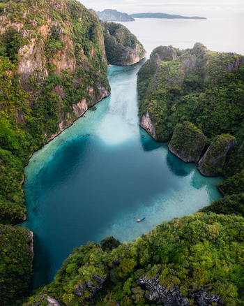 Aerial view of Pi Leh Bay with turquoise waters limestone cliffs and a small boat in Tambon Ao Nang Chang Wat Krabi Thailand. Aerial view of Pi Leh Bay with turquoise waters limestone cliffs and a small boat in Tambon Ao Nang Chang Wat Krabi Thailand.